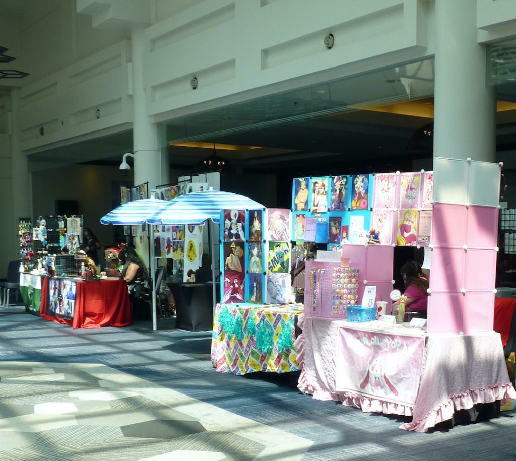 Artist Alley: Tables and artwork in hotel atrium