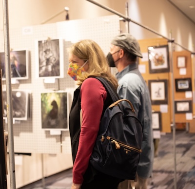 Convention attendees viewing artwork hung on panels